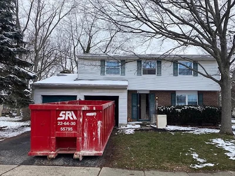 Day-one exterior photo with a dumpster in the driveway